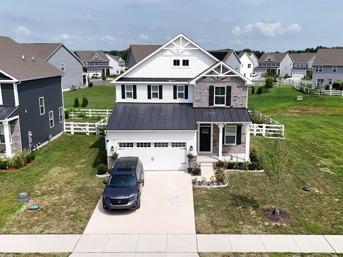 Aerial view of a two-storey house from the front, with its driveway, porch and lawn