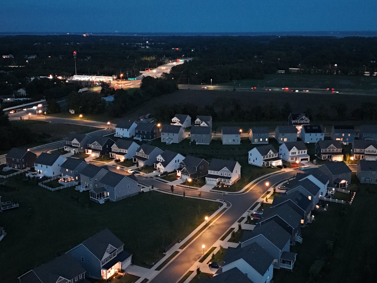 Dusk aerial of a curving residential street with the lights coming on