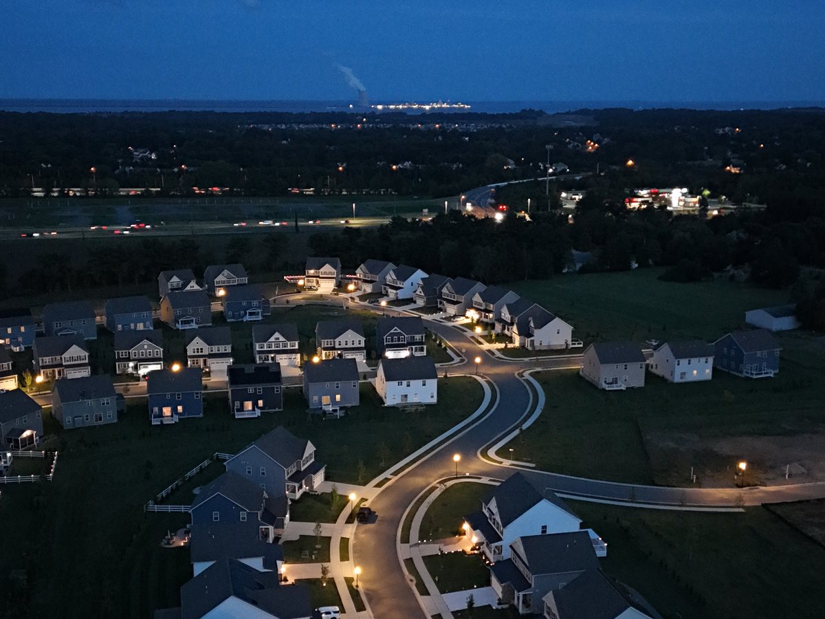 Twilight aerial over a neighbourhood, street lights on and a deep blue sky to the horizon