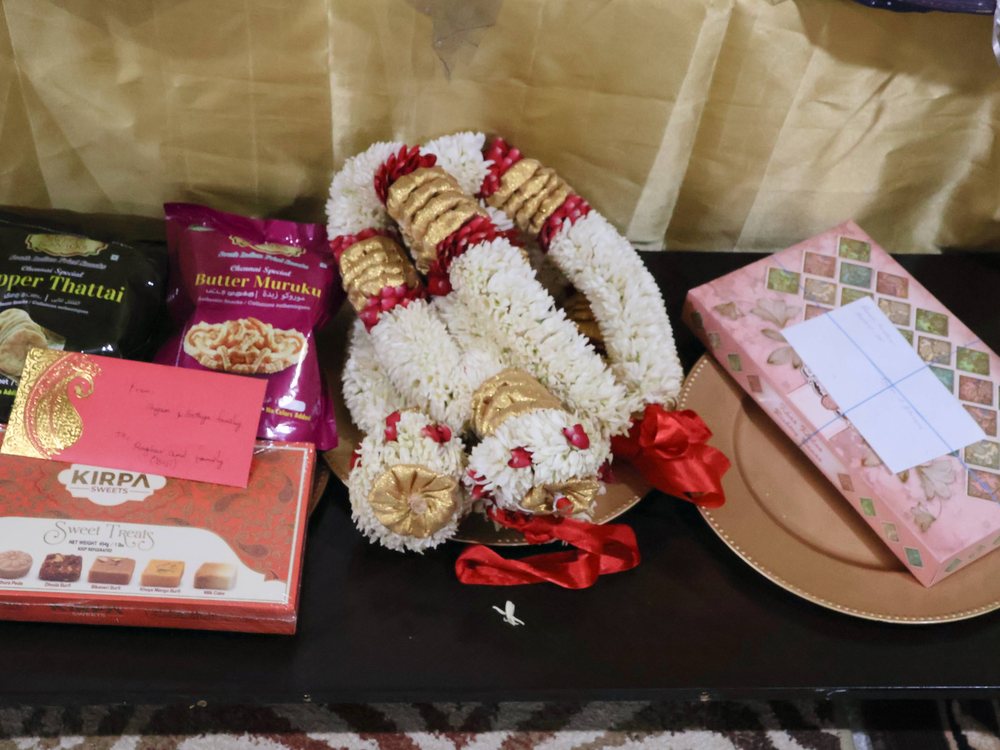 Engagement tray with jasmine garlands, sweet boxes and the invitation on a gold-draped table