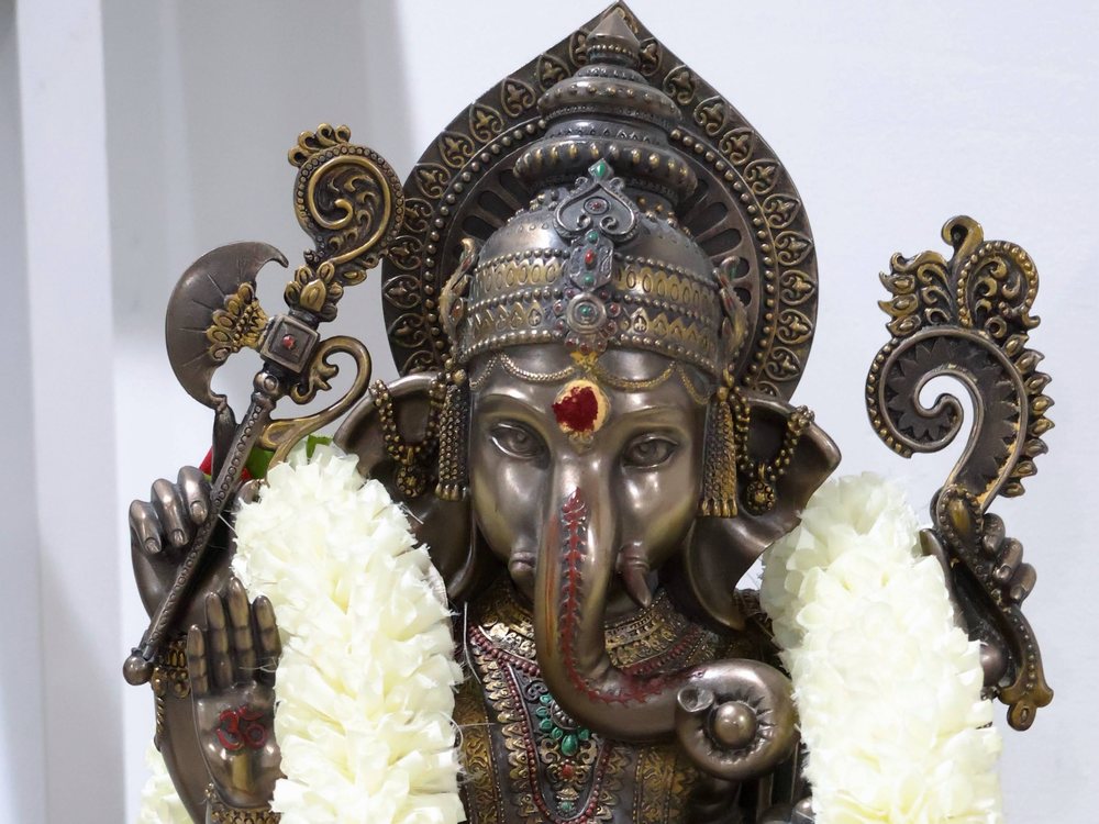 Bronze Ganesha idol dressed with a jasmine garland