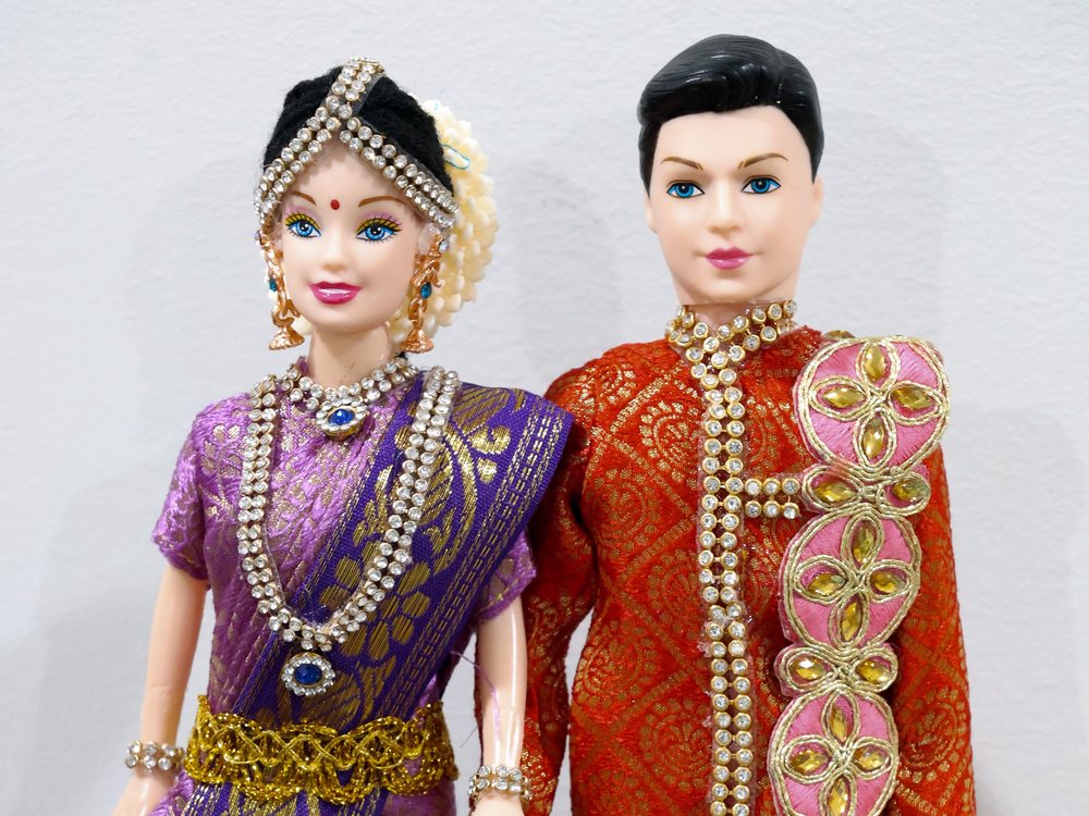 A pair of golu dolls dressed as bride and groom in silk and jewellery