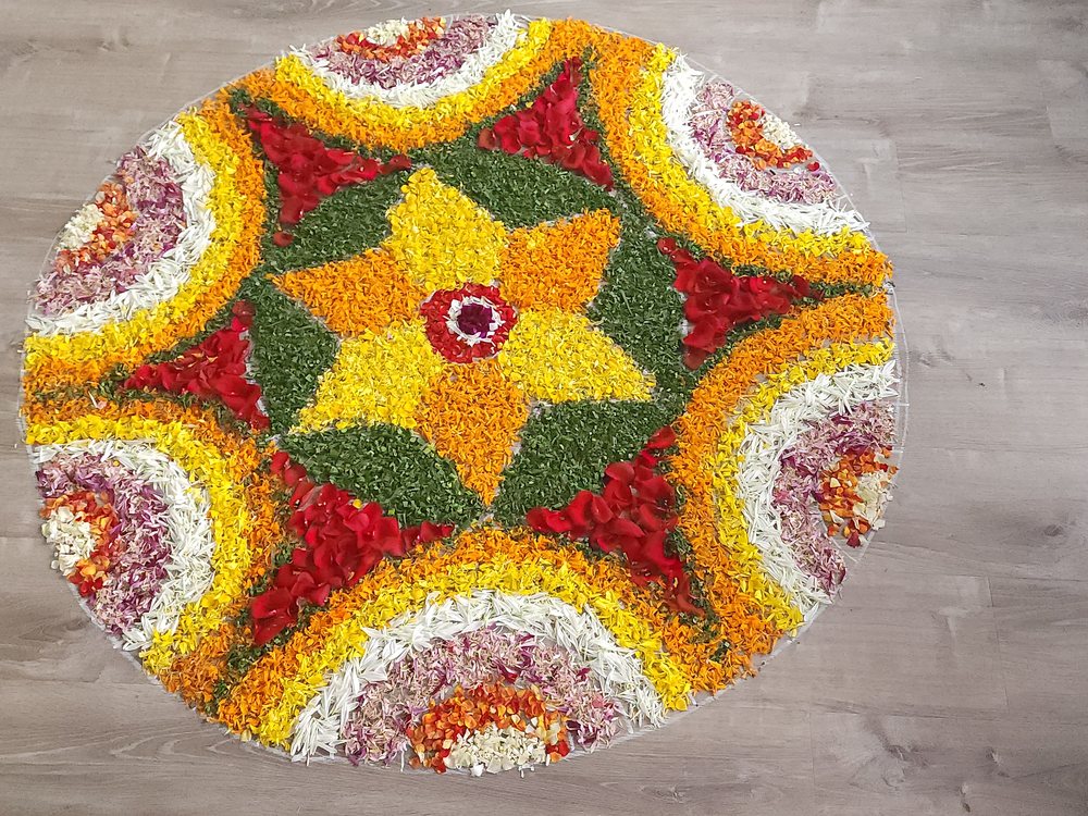Onam pookalam - a circular floral carpet laid out on a wooden floor
