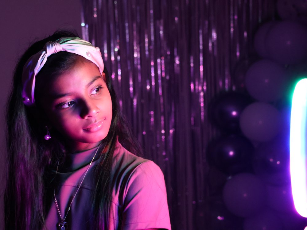 Portrait lit in pink and purple against a tinsel backdrop at a party