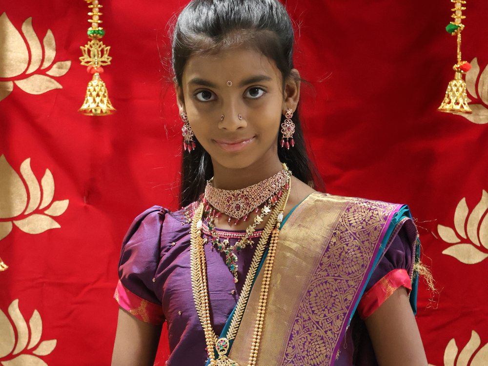 Portrait of a girl in traditional purple and gold silk against a red backdrop